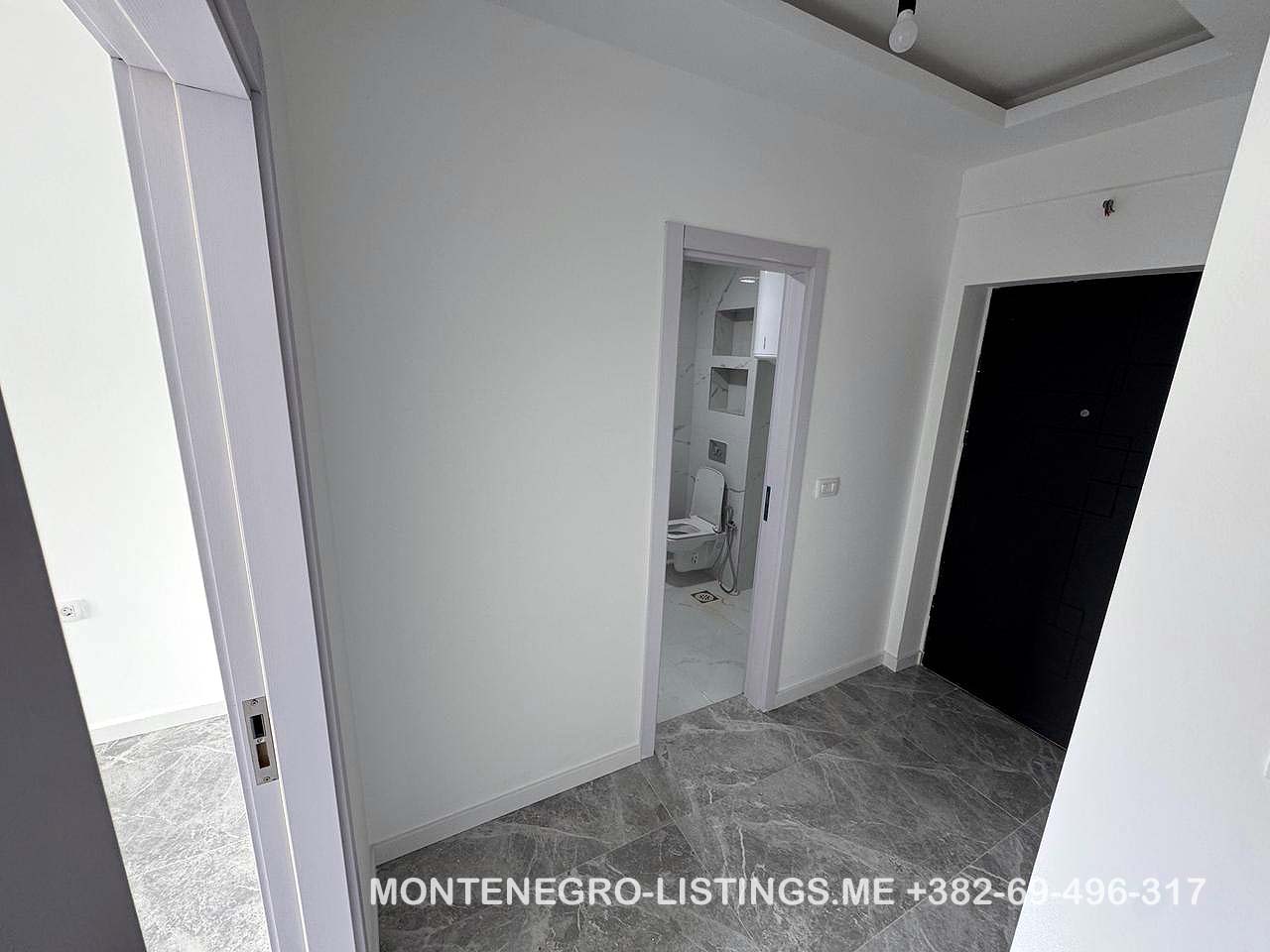 Modern hallway with gray tiled floors, white walls, 3 doors including a bathroom; prime Ulcinj real estate by immobilien.ekosphere.me.