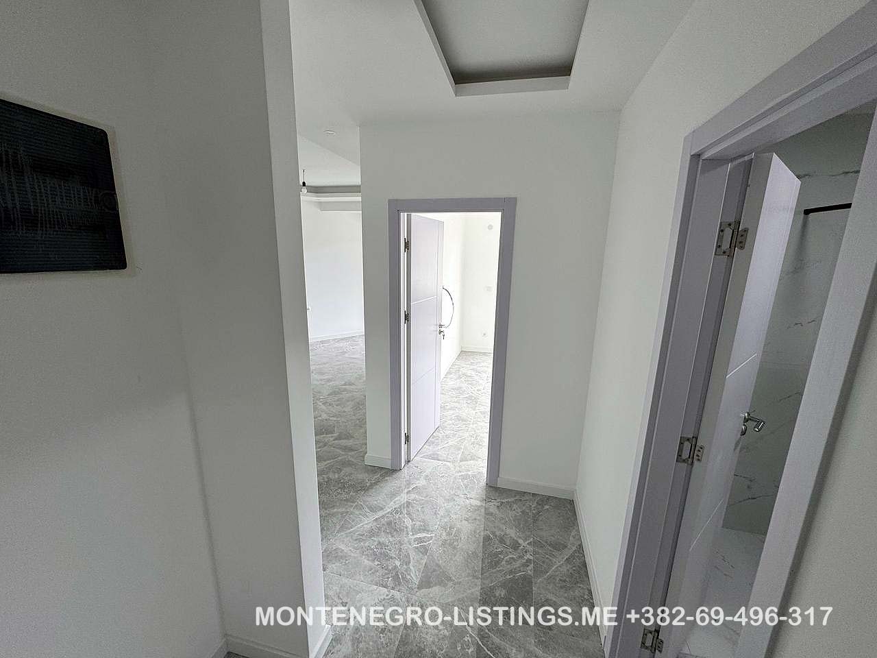 Modern hallway with gray tiles, white walls, and three open doorways in Ulcinj&mdash;exclusive at immobilien.ekosphere.me by ekosphere doo.