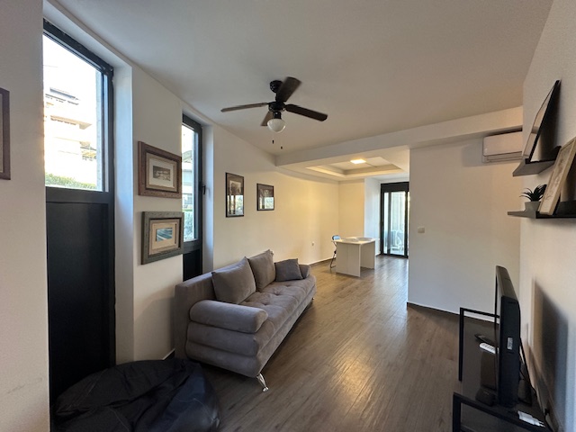 Elegant Ulcinj apartment: gray sofa, TV, wood floors, dining area & views&mdash;prime Montenegro real estate by Ekosphere on immobilien.ekosphere.me.