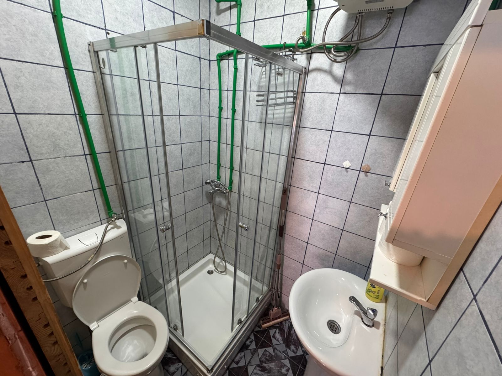 Modern bathroom in Ulcinj property: corner shower, wall sink, blue-accented tiles. Exclusive at immobilien.ekosphere.me by ekosphere doo.