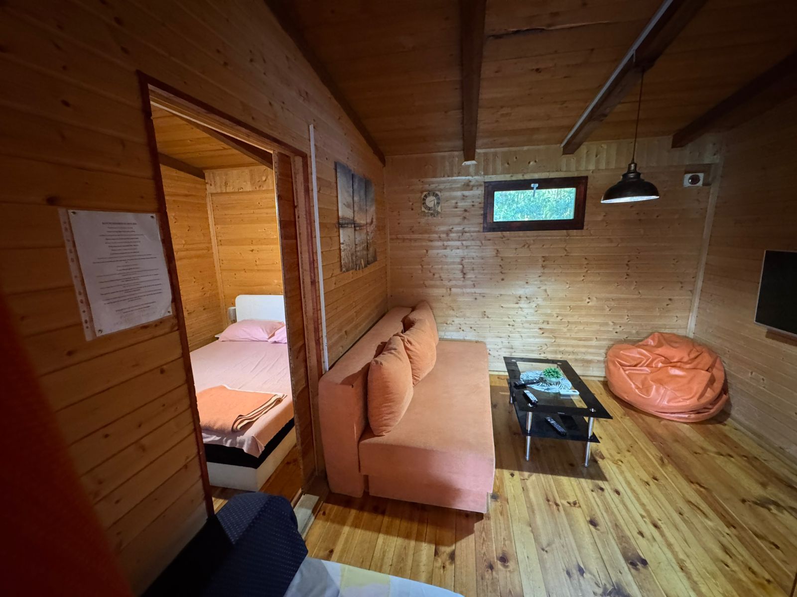 Charming Ulcinj cabin for sale&mdash;wood accents, orange sofa, modern TV, open bedroom. Invest with immobilien.ekosphere.me by ekosphere doo.