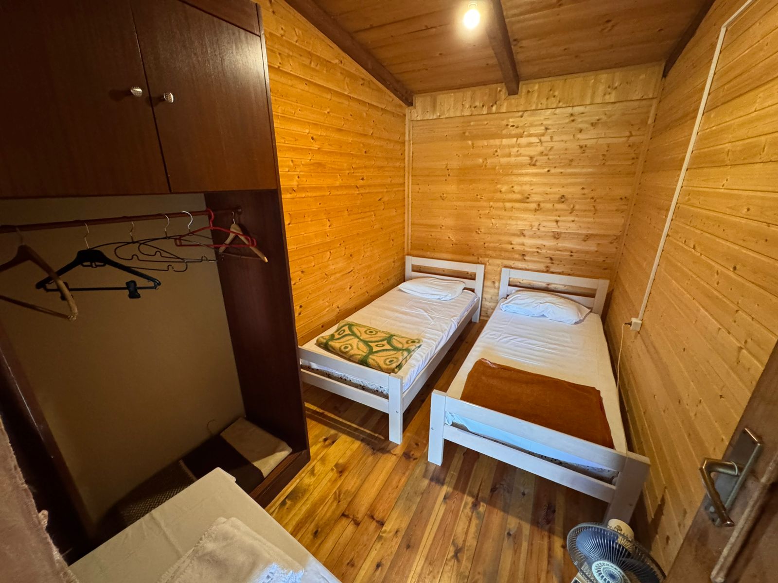 Charming wooden room in Ekosphere&rsquo;s Ulcinj property&mdash;two beds, wardrobe, modern amenities. Exclusive at immobilien.ekosphere.me.