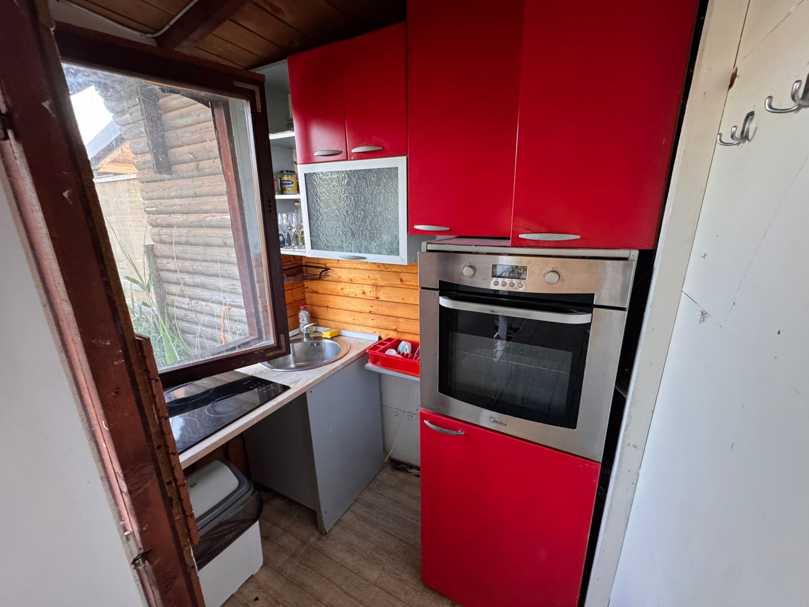 Chic Ulcinj kitchen: red cabinets, stainless oven, wood accents. Bright and inviting. Exclusive on immobilien.ekosphere.me by Ekosphere doo.