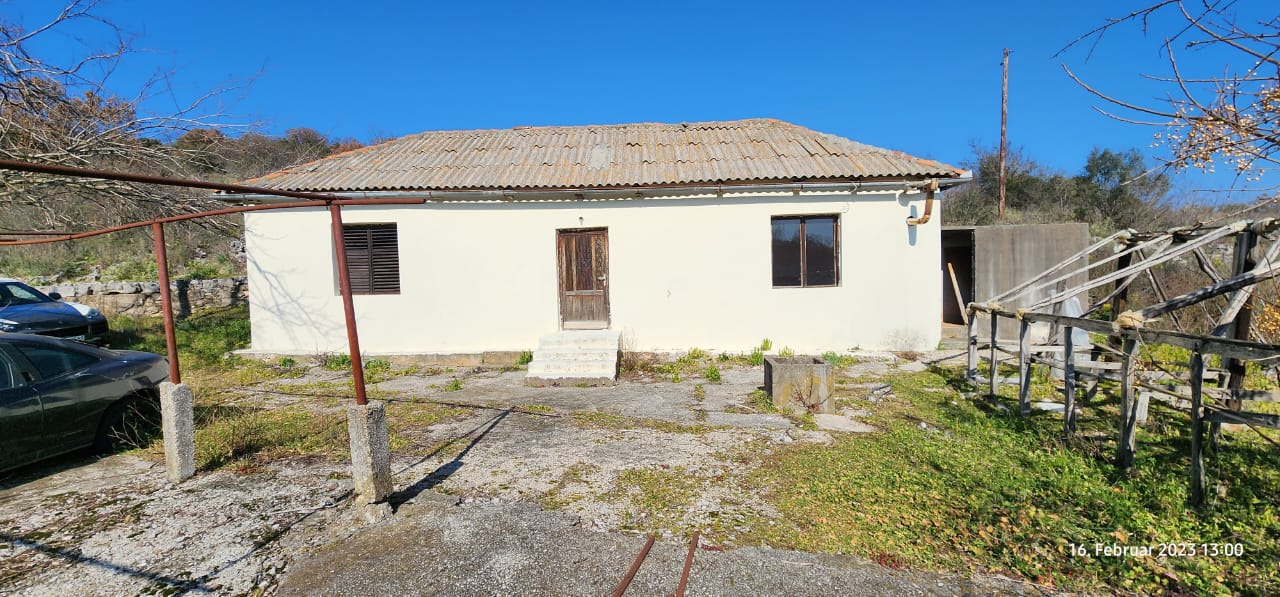 Charming single-story house with cream walls, two windows, central wooden door&mdash;ideal Ulcinj real estate investment. Montenegro-listings.me by ekosphere doo.