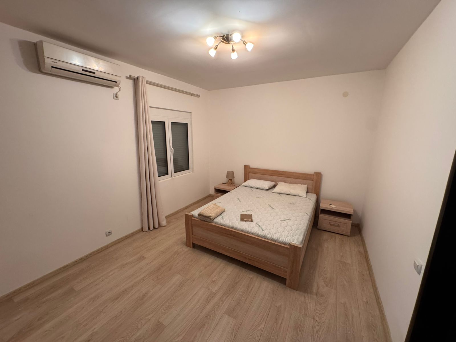 Modern Ulcinj bedroom with light wood floors, double bed, AC, and elegant finishes&mdash;prime Montenegro real estate by Ekosphere doo.