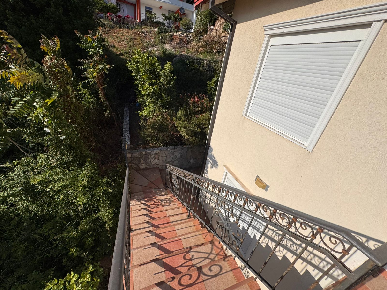 Elegant terracotta-tiled staircase with black railing and lush greenery, a prime Ulcinj real estate feature&mdash;immobilien.ekosphere.me by ekosphere doo.