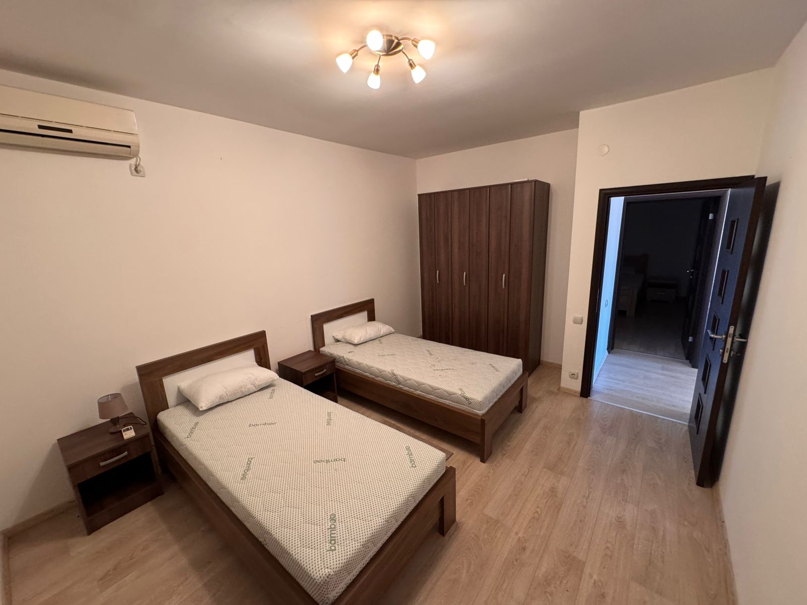 Modern Ulcinj bedroom with two single beds, wood flooring, AC, wardrobe&mdash;ideal Montenegro investment via immobilien.ekosphere.me.