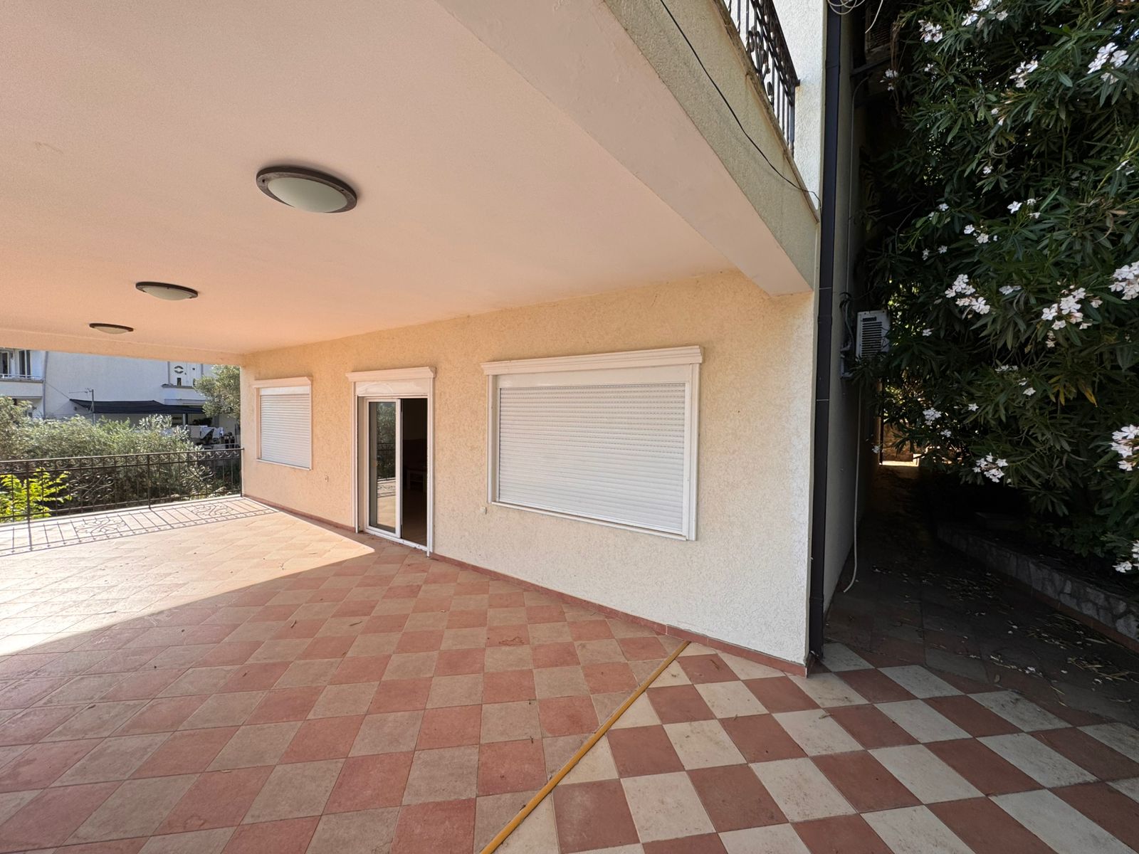 Stylish covered patio with checkered tile floor, white shutters, and glass door&mdash;top Ulcinj real estate at immobilien.ekosphere.me by Ekosphere doo.
