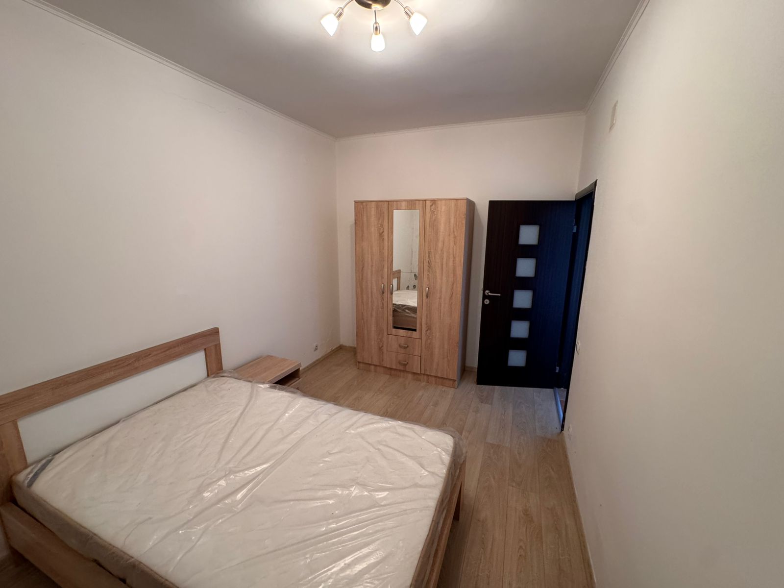 Modern Ulcinj bedroom with wooden bed, mirrored wardrobe, and sleek flooring&mdash;prime investment at immobilien.ekosphere.me by Ekosphere DOO.