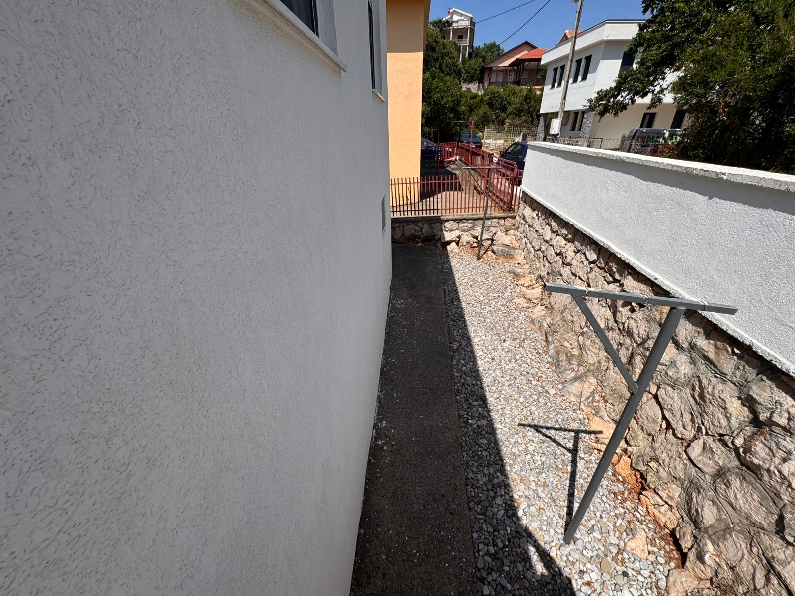 Prime Ulcinj property: gravel walkway & concrete path between buildings, metal structure, stone wall&mdash;exclusive at immobilien.ekosphere.me by ekosphere doo.