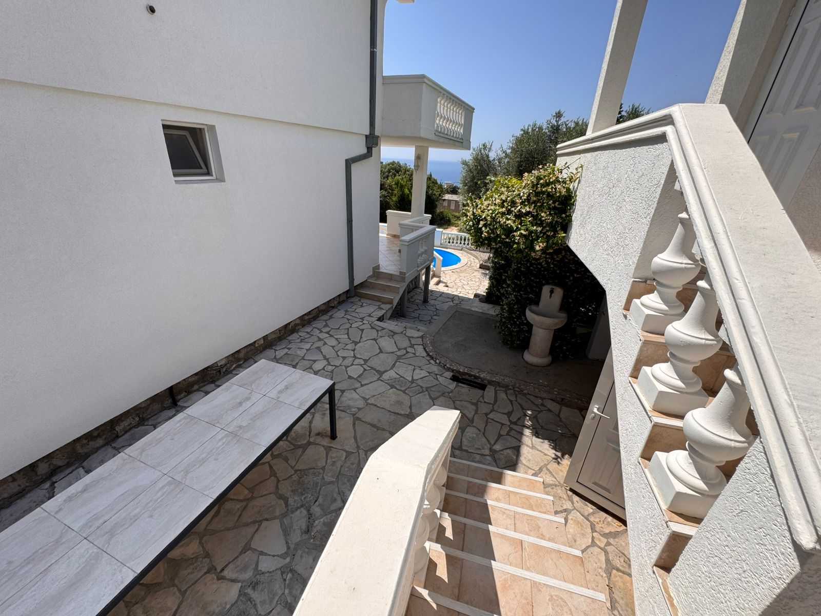 Elegant stone steps and walkway lead to a sunny tiled patio and pool&mdash;prime Ulcinj real estate with immobilien.ekosphere.me by Ekosphere.