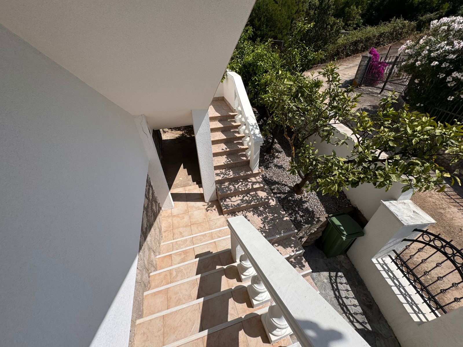Inviting tiled staircase with white railings leads to lush garden&mdash;prime investment in Ulcinj. Listed by ekosphere doo at immobilien.ekosphere.me.