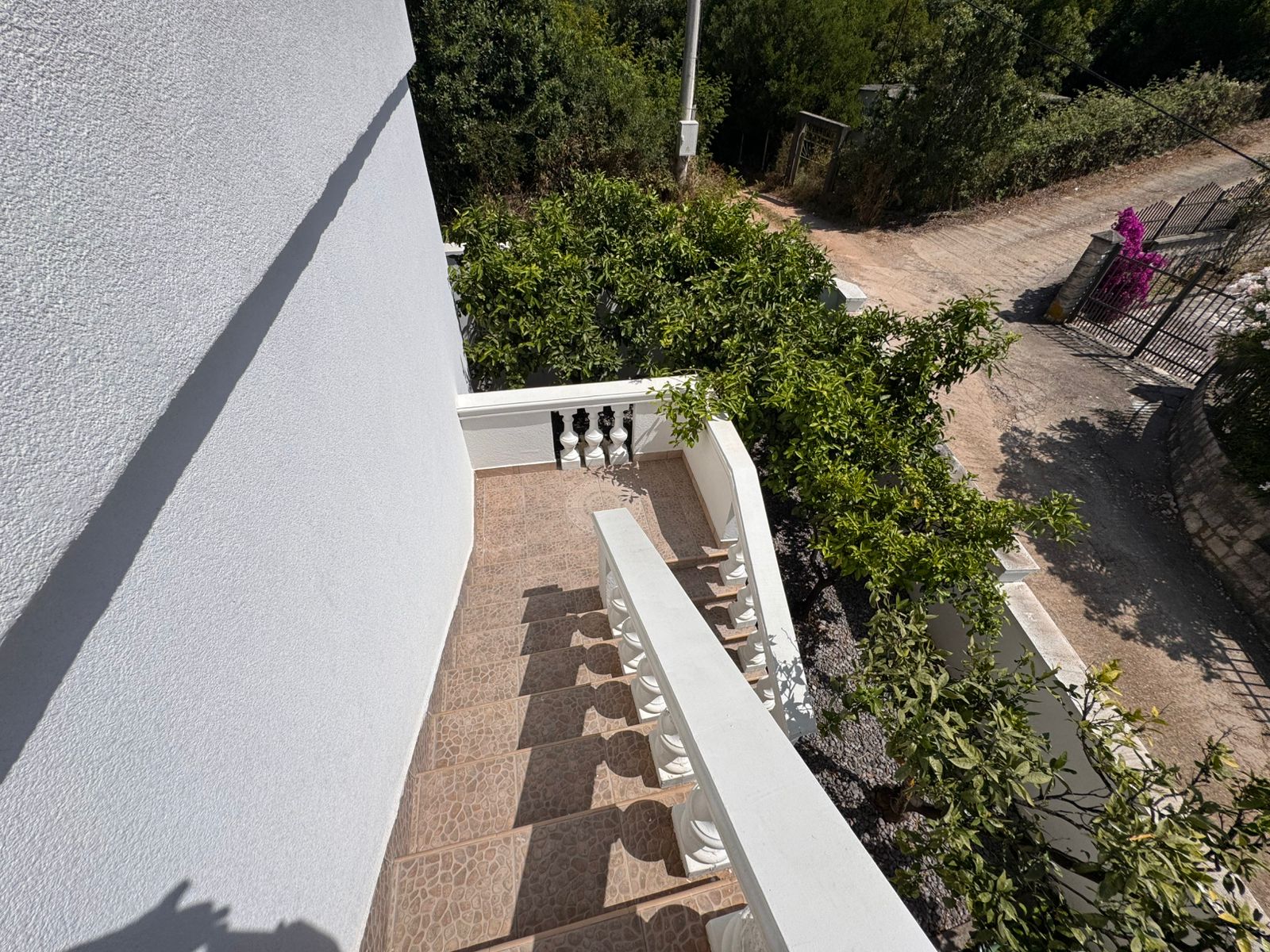 Modern outdoor staircase with white railings, brown tiles, and lush greenery&mdash;prime Ulcinj property via immobilien.ekosphere.me by Ekosphere.