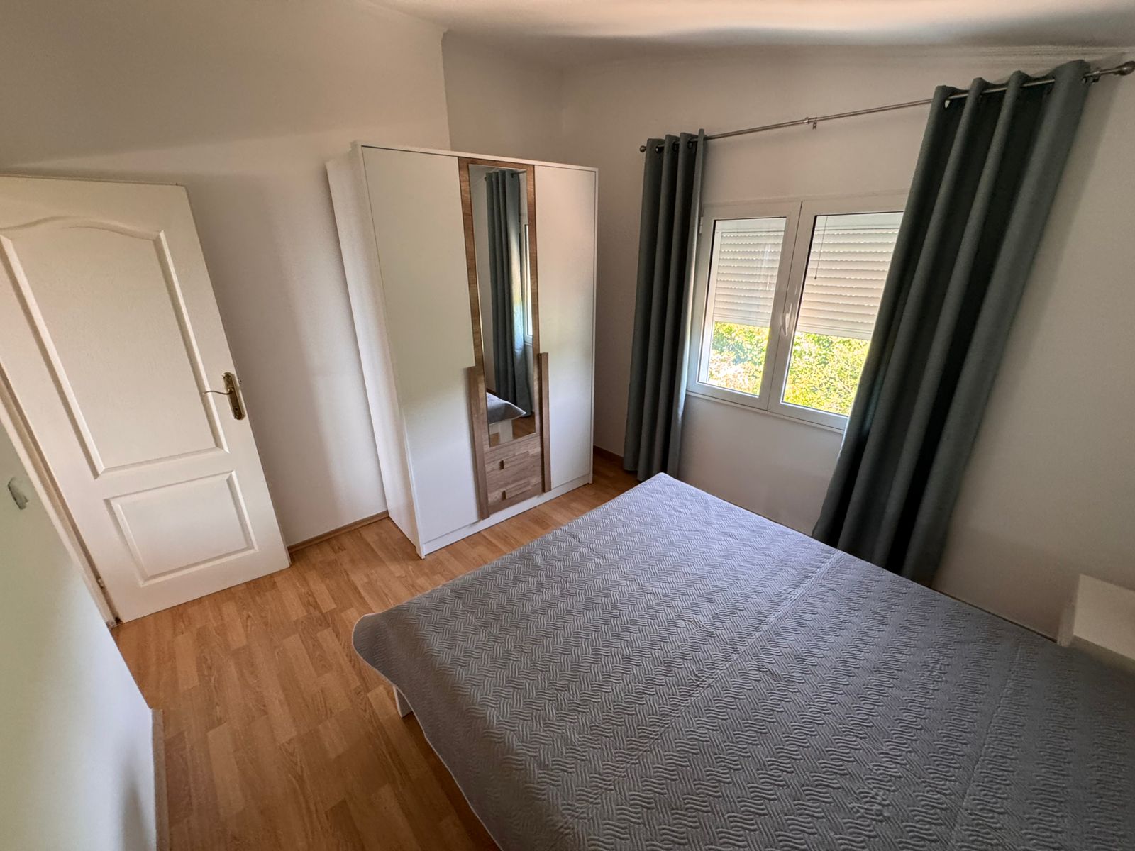 Stylish Ulcinj bedroom: wooden flooring, gray bed, mirrored wardrobe. Invest in prime Montenegro real estate by Ekosphere on immobilien.ekosphere.me.