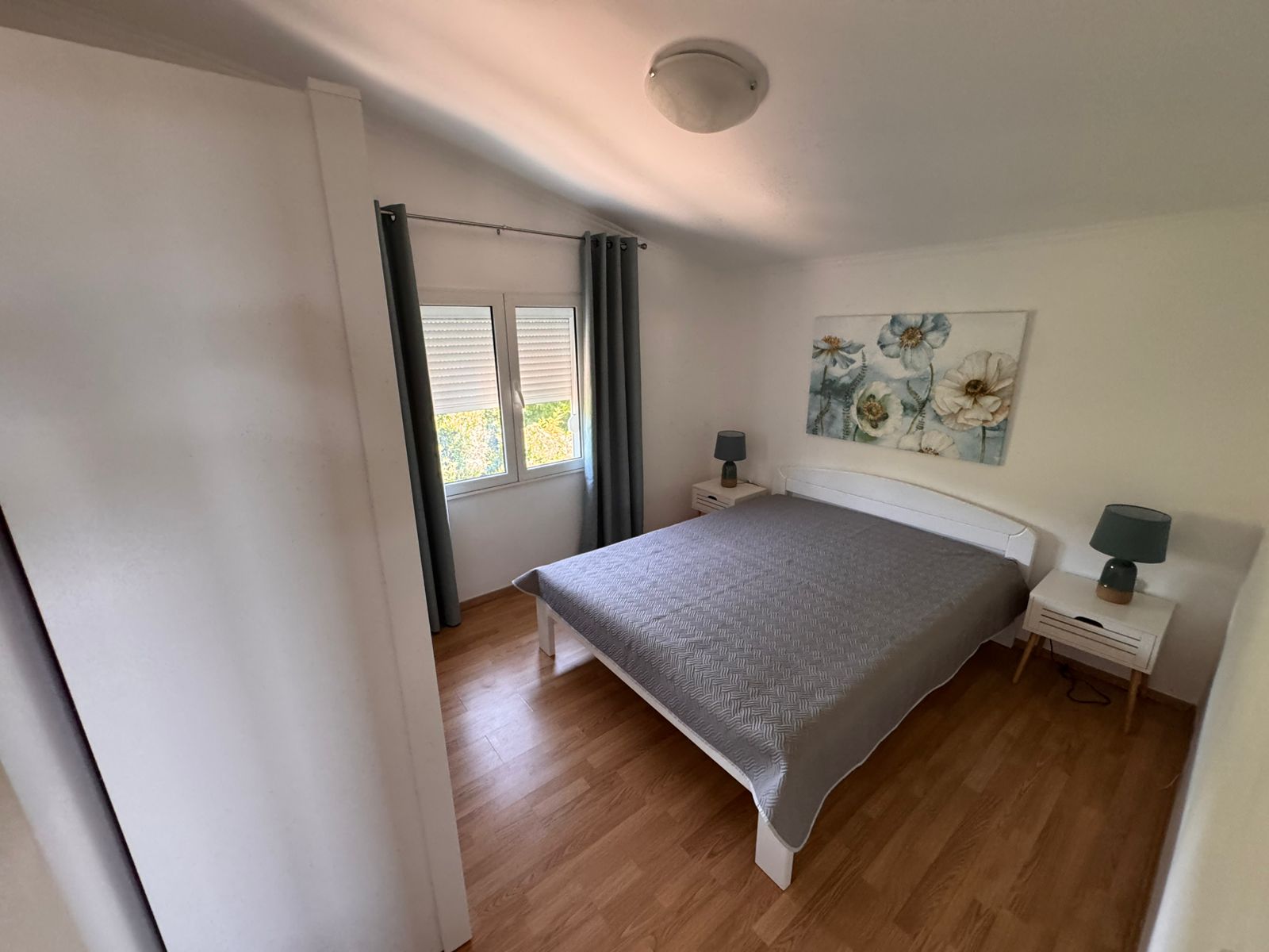 Elegant Ulcinj bedroom with hardwood floors, stylish bed, blue lamps; prime real estate&mdash;exclusively on immobilien.ekosphere.me by ekosphere doo.
