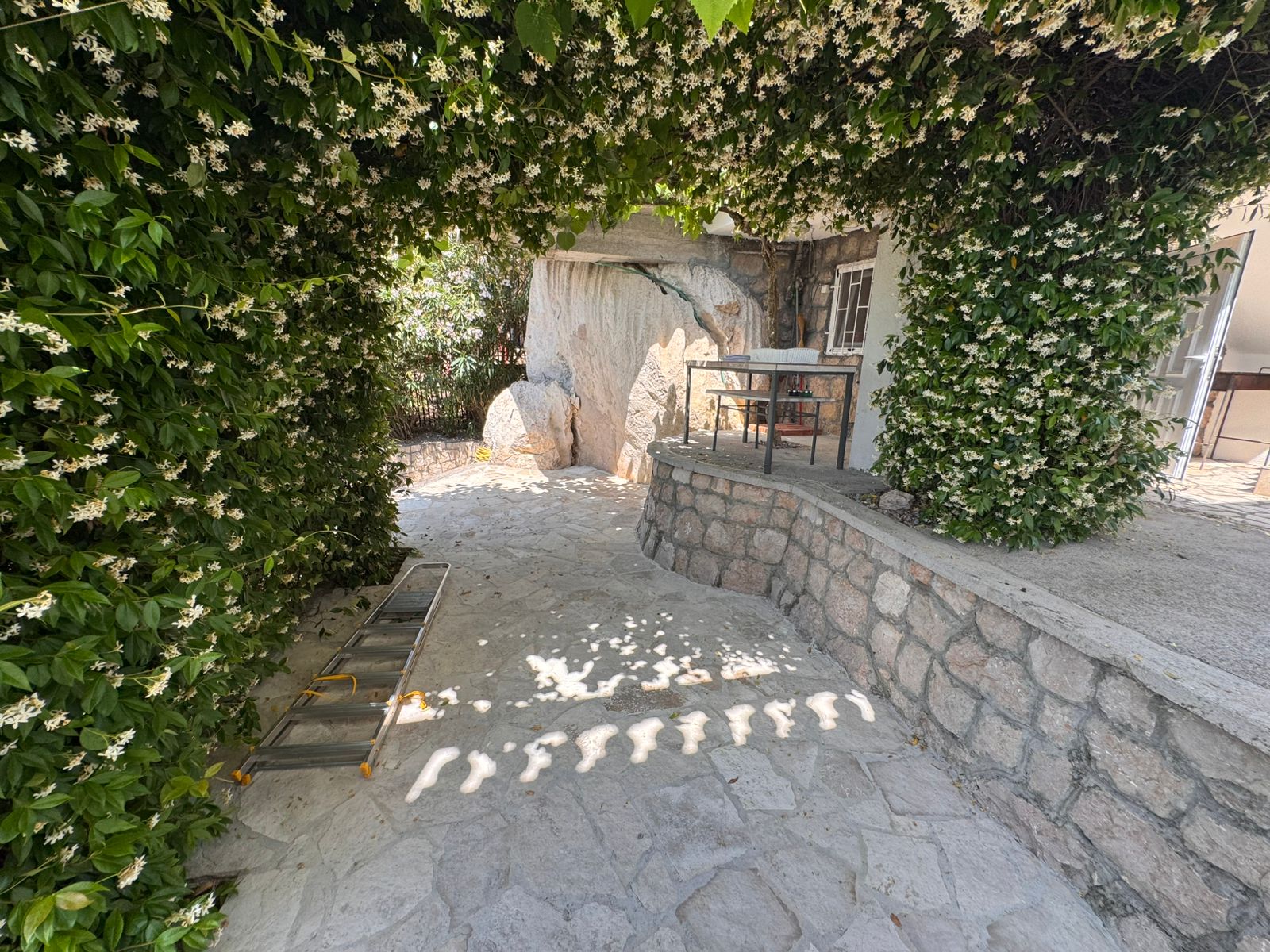 Elegant stone patio in Ulcinj, shaded by lush green archway. Ideal investment&mdash;exclusive at immobilien.ekosphere.me by Ekosphere doo.