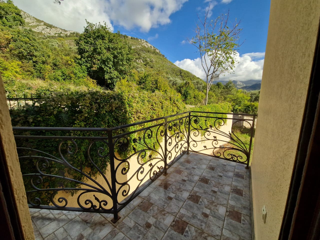 Elegant tiled balcony with ornate railing, lush garden views, and rolling hills&mdash;prime Ulcinj real estate on immobilien.ekosphere.me by ekosphere doo.