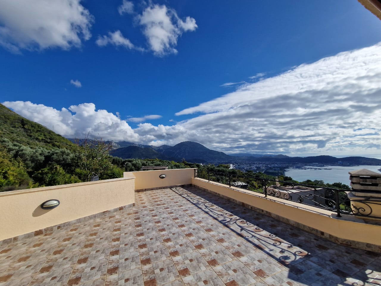 Luxury tiled terrace with yellow railing, panoramic sea, town, and green hill views&mdash;prime Ulcinj real estate by ekosphere doo.