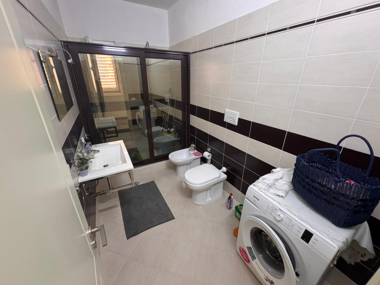 Modern bathroom in Ulcinj, Montenegro: elegant tiled walls, glass shower, bidet, premium fixtures; exclusive at immobilien.ekosphere.me by Ekosphere doo.