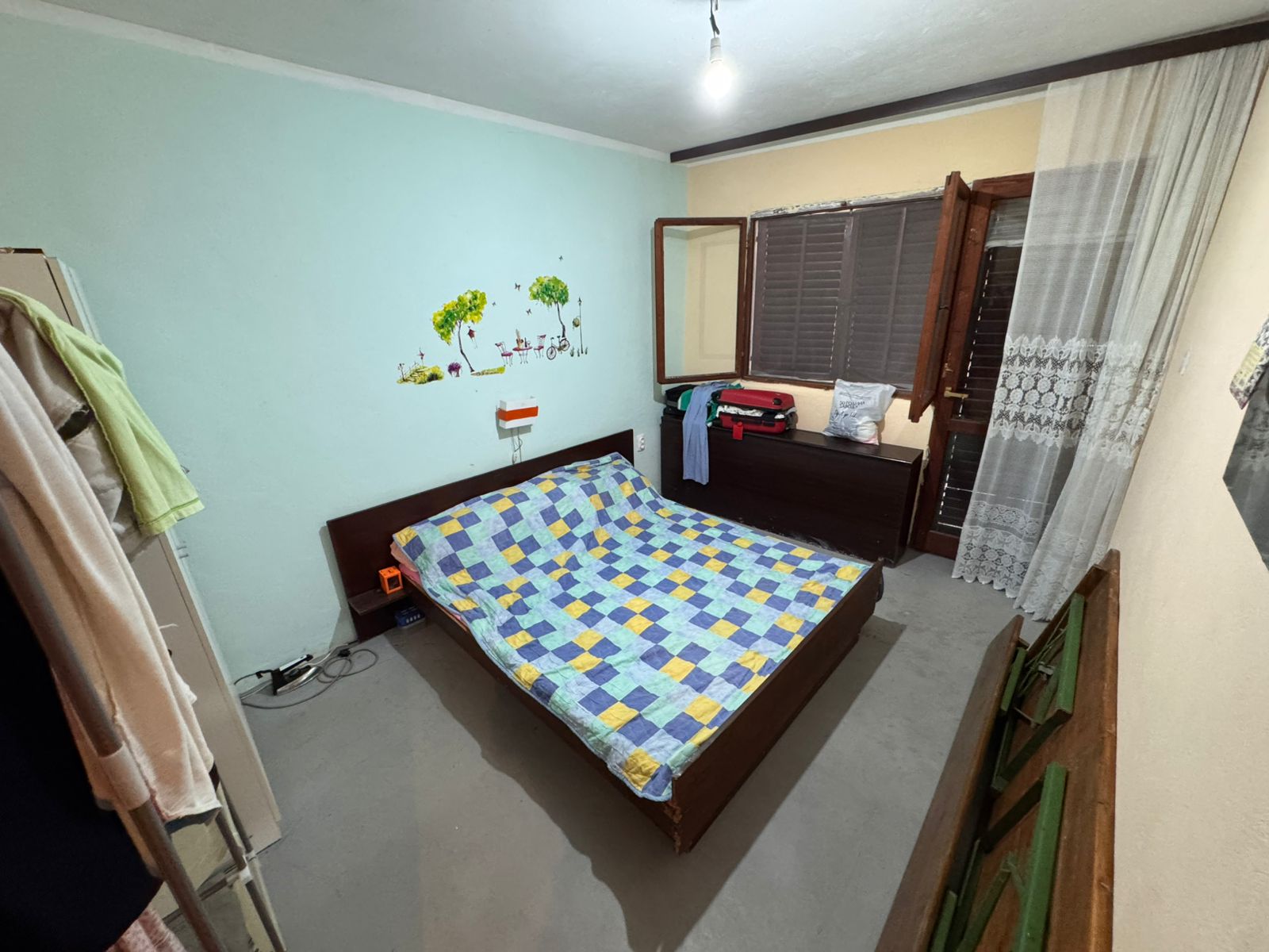 Charming Ulcinj bedroom with double bed, bright quilt, storage dresser & open window. Ideal Montenegro property by Ekosphere on immobilien.ekosphere.me.