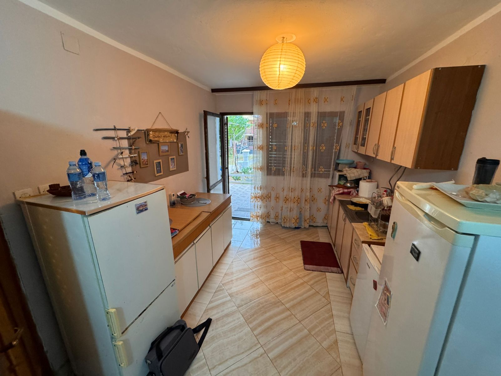 Modern compact kitchen in Ulcinj real estate, with white fridge, sleek cabinetry, bright lighting&mdash;offered by immobilien.ekosphere.me.