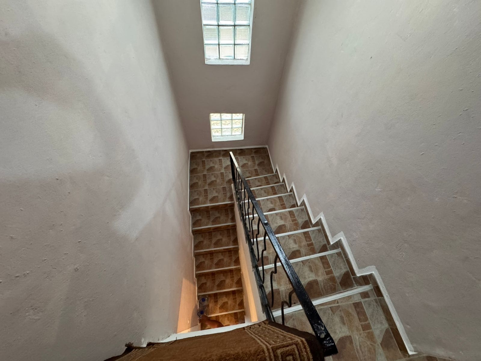 Modern staircase with brown tiles, black handrail, and skylights&mdash;bright, elegant Ulcinj real estate by ekosphere doo, immobilien.ekosphere.me.
