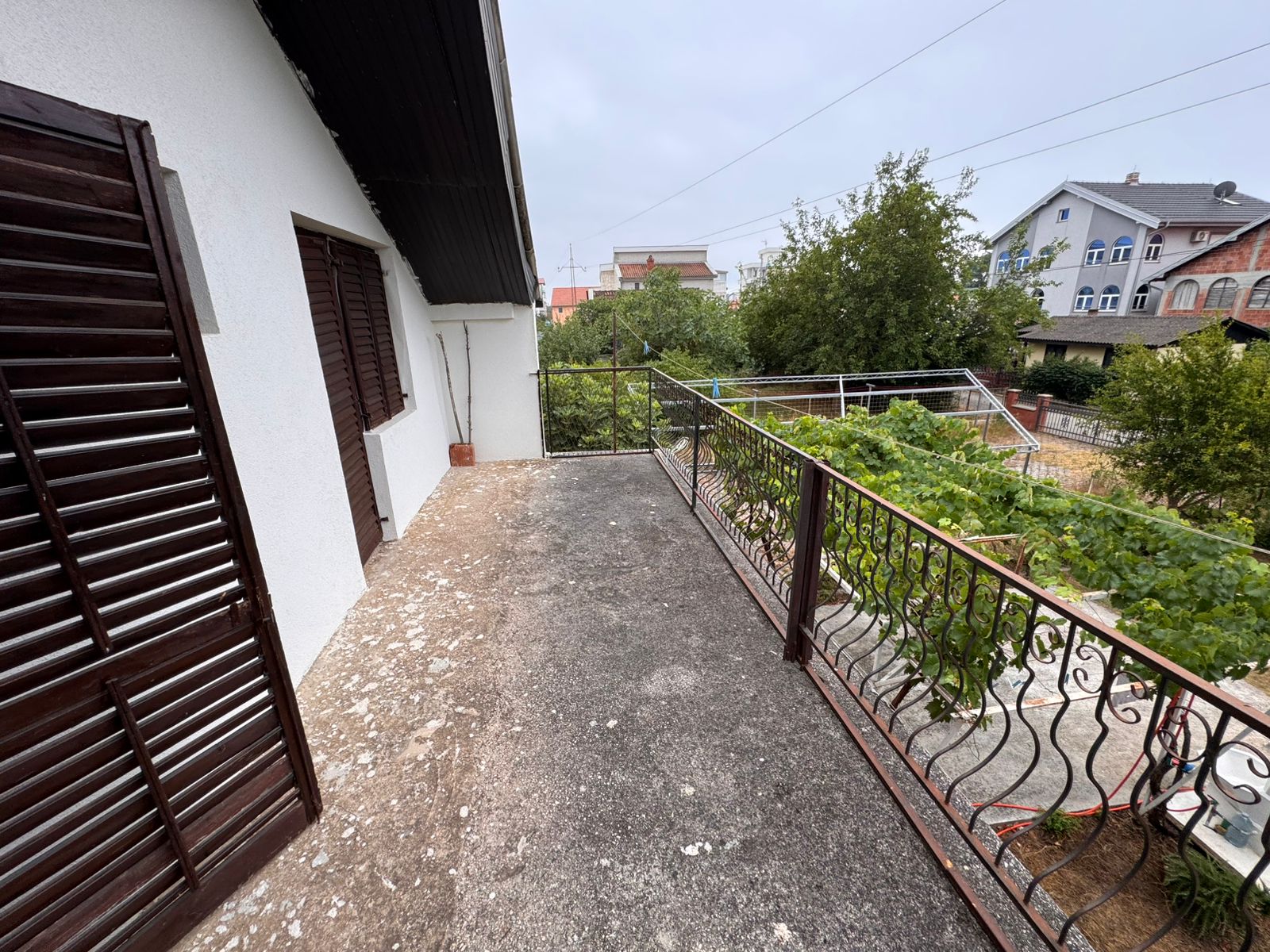 Modern concrete balcony with metal railing and lush garden views, prime Ulcinj property near amenities; listed on immobilien.ekosphere.me.