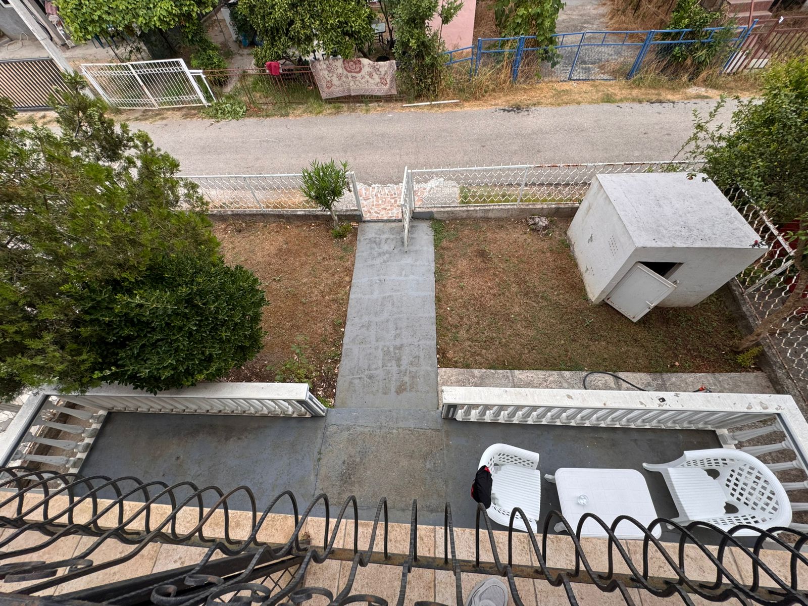 Upper balcony view in Ulcinj: private yard, stone path, white shed. Invest with immobilien.ekosphere.me, a project of Ekosphere doo.