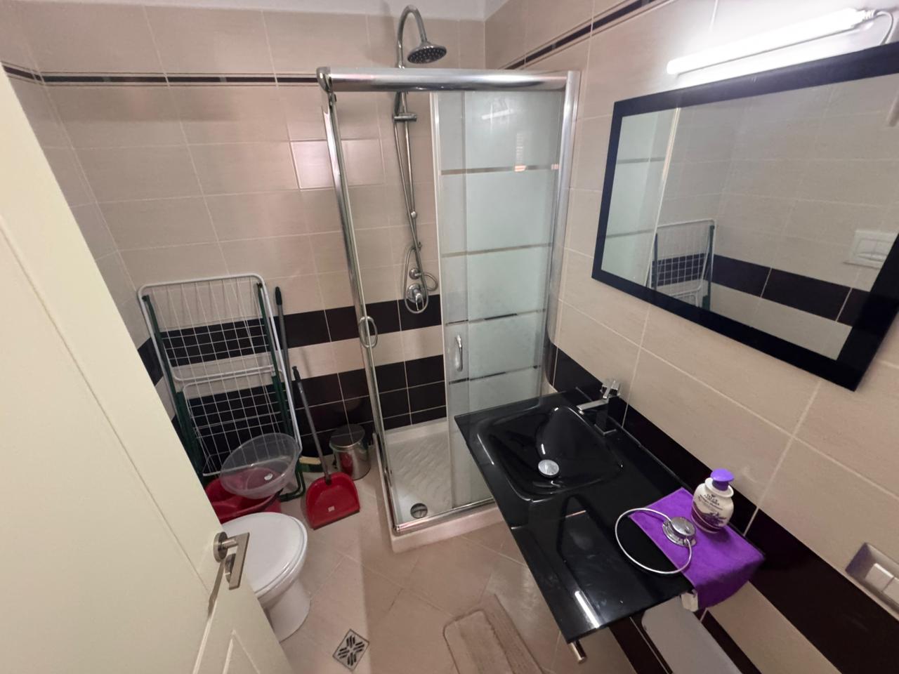 Modern bathroom in Ulcinj Montenegro real estate with glass shower, black sink, chic tiles. Listed on immobilien.ekosphere.me by ekosphere doo.