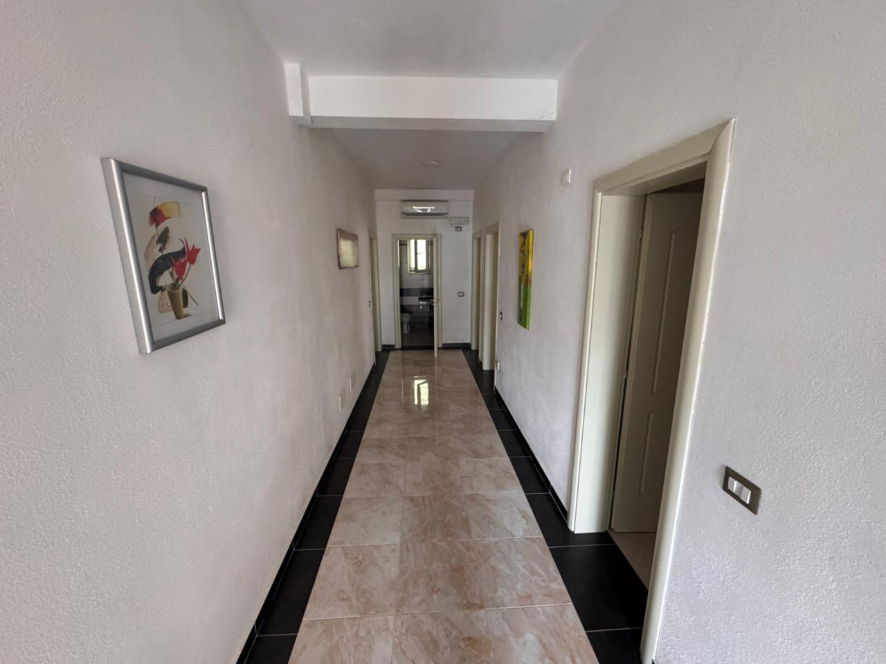 Elegant hallway with bright walls, glossy tiles, doors, and modern art&mdash;ideal Ulcinj investment. Listed by immobilien.ekosphere.me of Ekosphere doo.