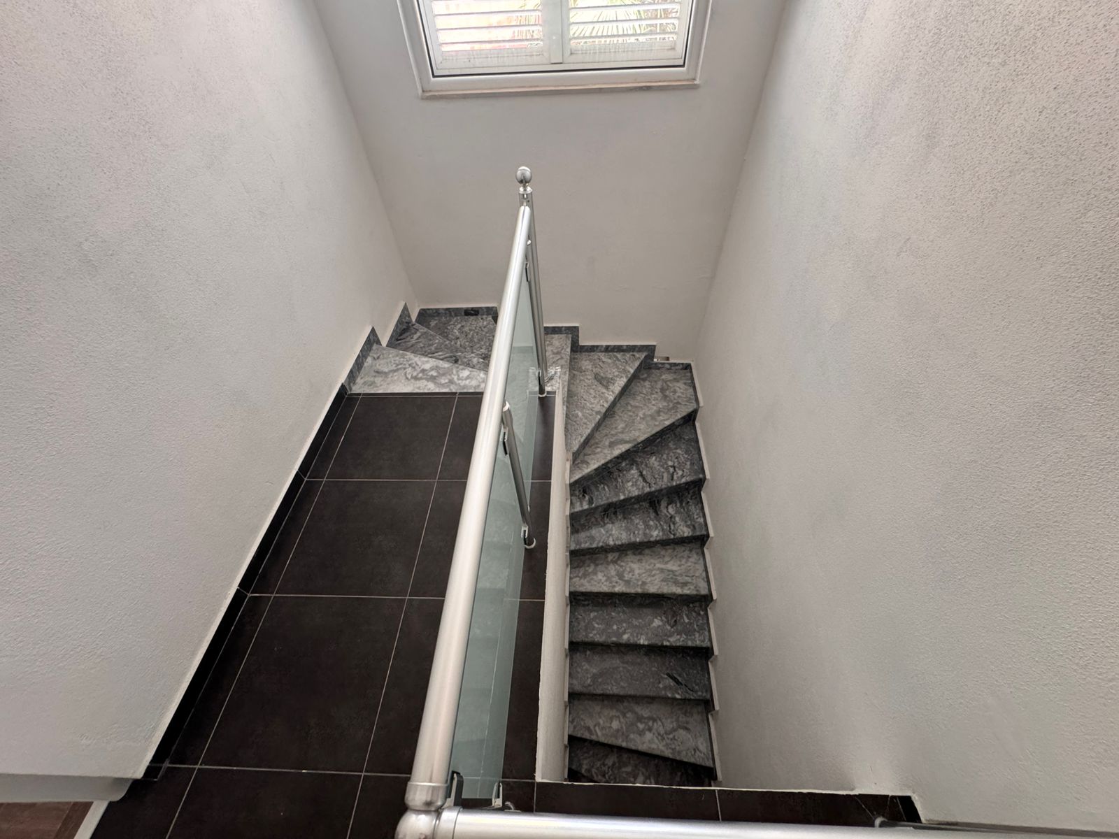 Elegant Ulcinj property: dark marble staircase with glass railing, white walls, exclusive listing on immobilien.ekosphere.me by ekosphere doo.