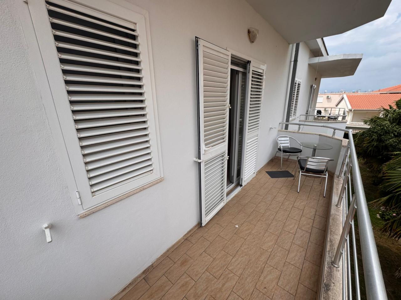 Ulcinj property for sale: tiled balcony, glass table, striped chairs, palm views. Ideal Montenegro real estate from ekosphere doo.