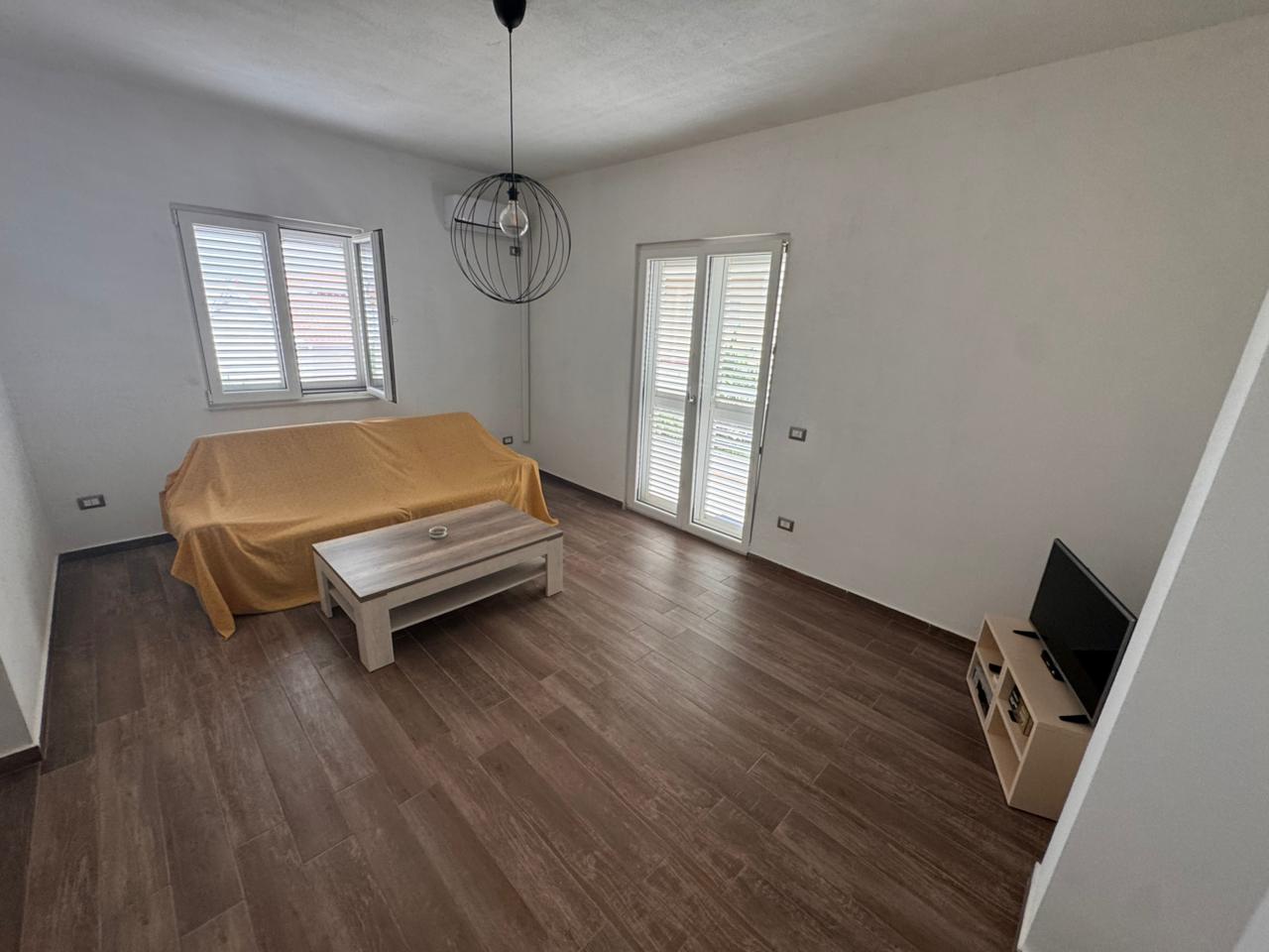 Modern living room in Ulcinj, Montenegro with wood floors, yellow sofa, natural light; a smart real estate investment by ekosphere doo.
