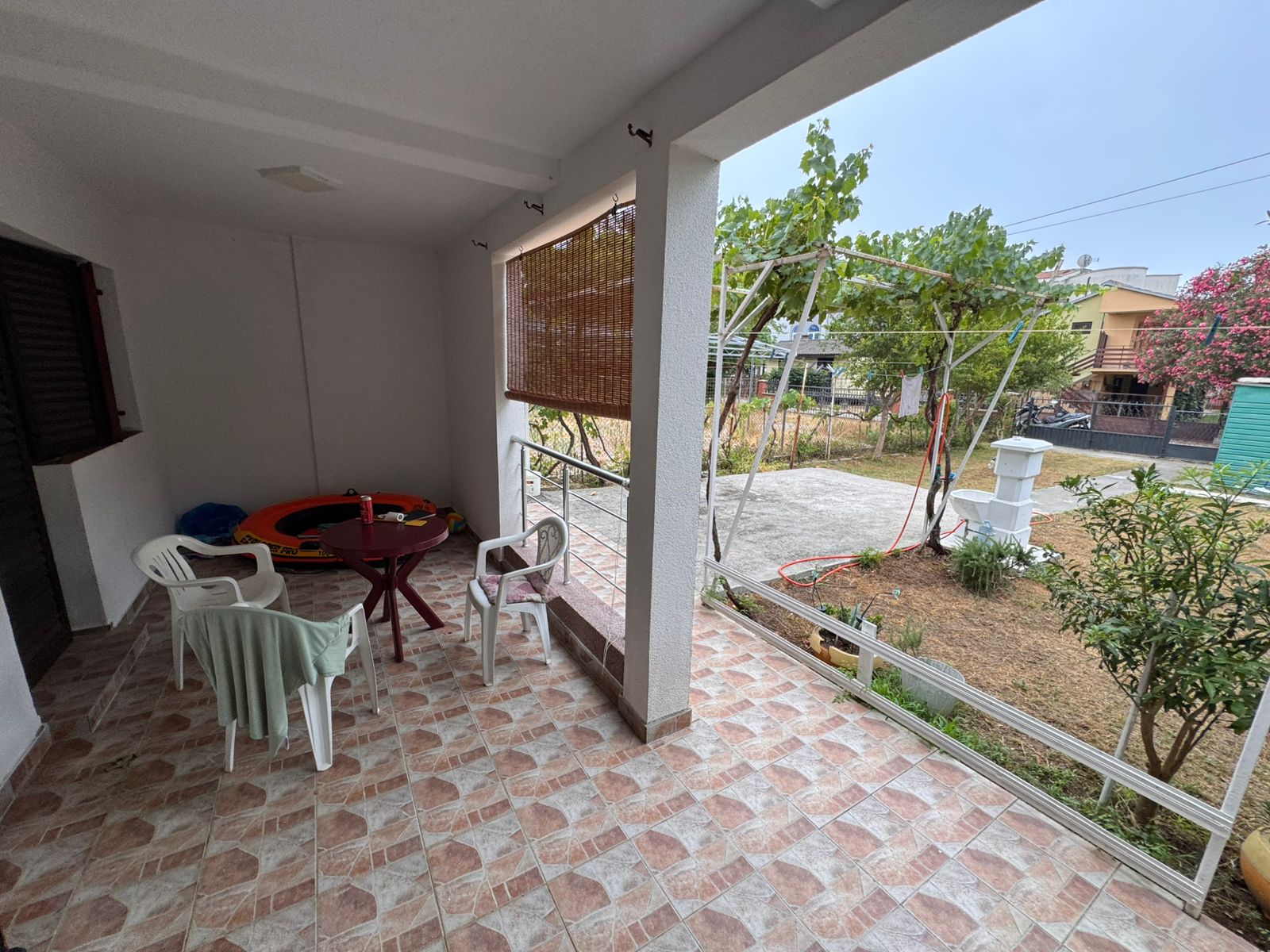 Elegant tiled patio with white columns, ideal for relaxing and entertaining in Ulcinj. Listed by Ekosphere on immobilien.ekosphere.me.