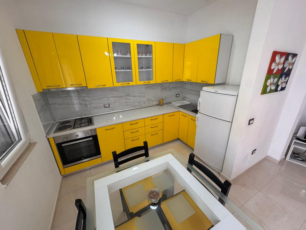 Contemporary Ulcinj kitchen with yellow cabinetry, marble backsplash, and dining area&mdash;exclusive listing on immobilien.ekosphere.me by ekosphere doo.