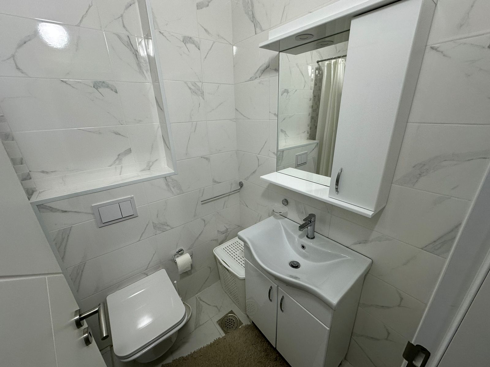 Modern bathroom in Ulcinj with marble tiles, wall-mounted toilet, elegant vanity&mdash;exclusive eco-property by ekosphere at immobilien.ekosphere.me.