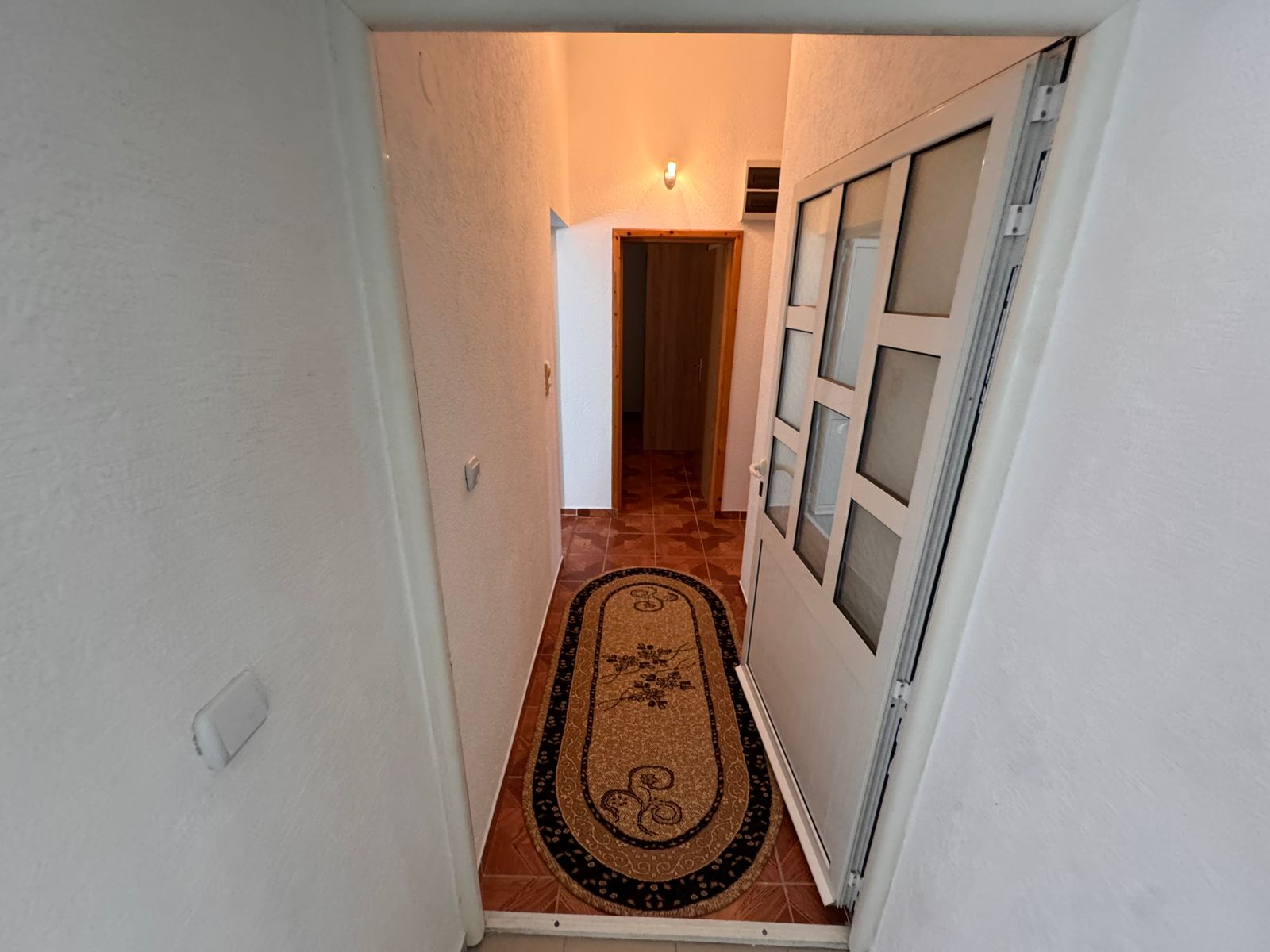 Modern Ulcinj property: bright hallway, white walls, classic brown tile floors, ideal investment. Exclusive on immobilien.ekosphere.me by ekosphere doo.
