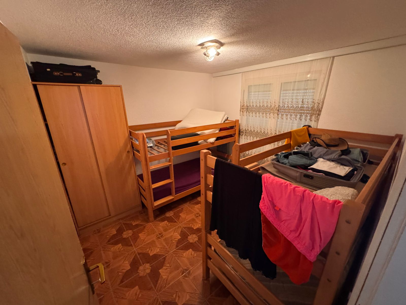 Charming Ulcinj property: compact bedroom with 2 wooden bunk beds, wardrobe, stylish tiles. Discover on immobilien.ekosphere.me by ekosphere doo.