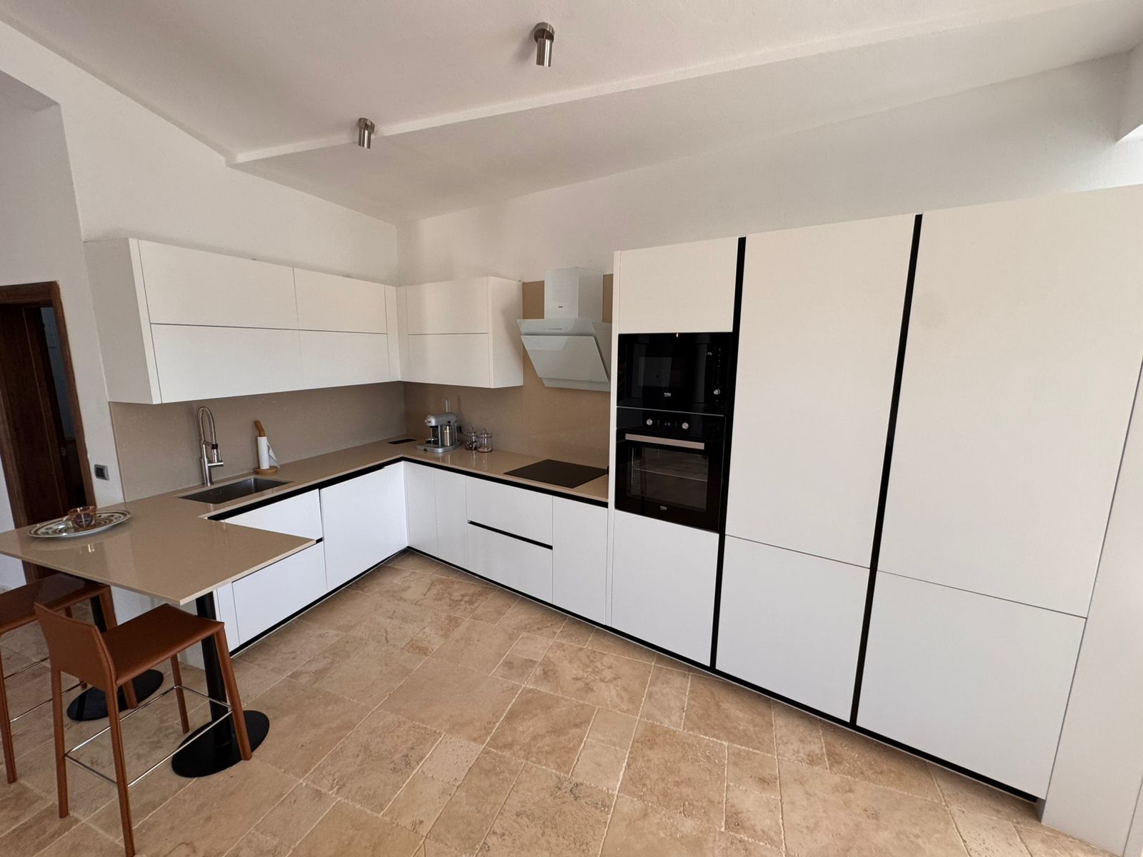 Contemporary kitchen in Ulcinj with white cabinetry, modern appliances, island seating; ideal Montenegro real estate by immobilien.ekosphere.me (Ekosphere doo).