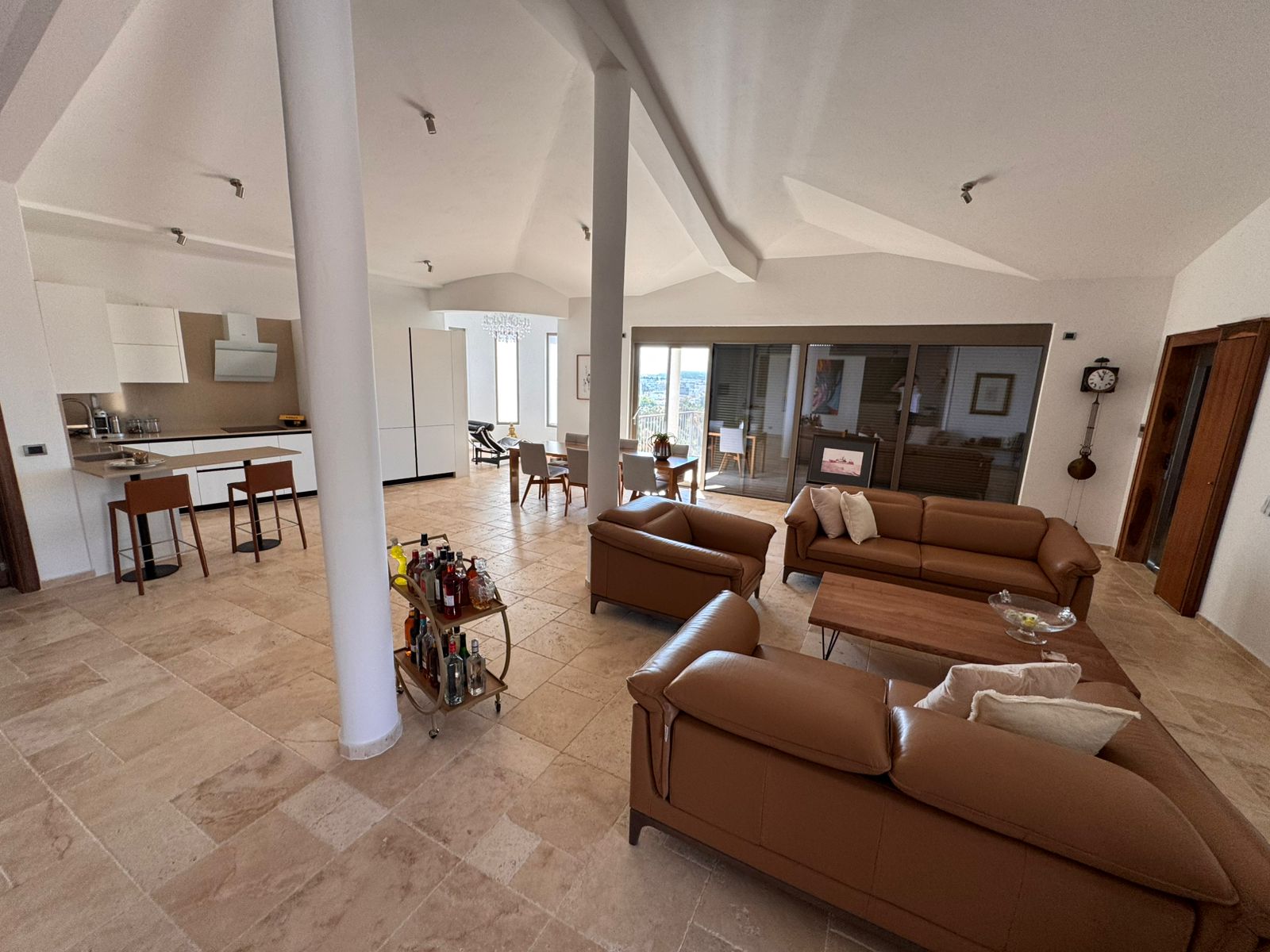 Elegant modern living room in Ulcinj, Montenegro&mdash;tan leather sofas, open kitchen, large windows&mdash;listed by immobilien.ekosphere.me.