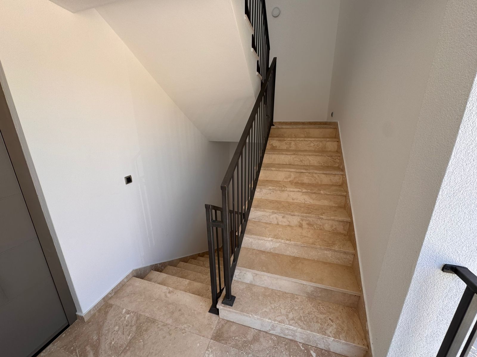Elegant staircase with beige marble steps and black railings, featured in luxury Ulcinj properties at immobilien.ekosphere.me by Ekosphere.