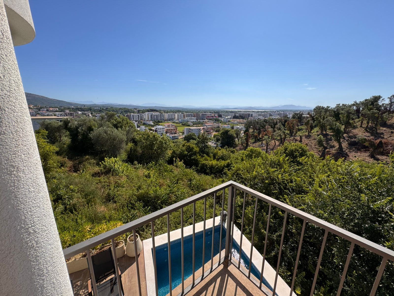 Stunning balcony view at Ekosphere: pool, lush greenery, residences & mountains in Ulcinj. Exclusive on immobilien.ekosphere.me by Ekosphere DOO.