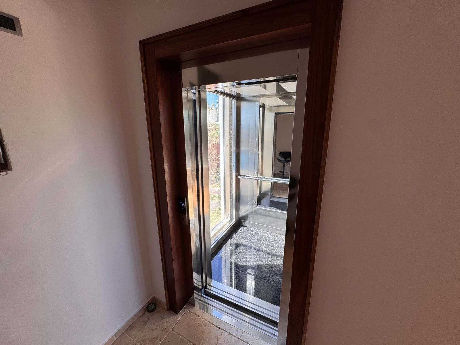 Luxurious elevator with glass walls, mirrored ceiling, and beige tiles&mdash;premium Ulcinj real estate by immobilien.ekosphere.me.