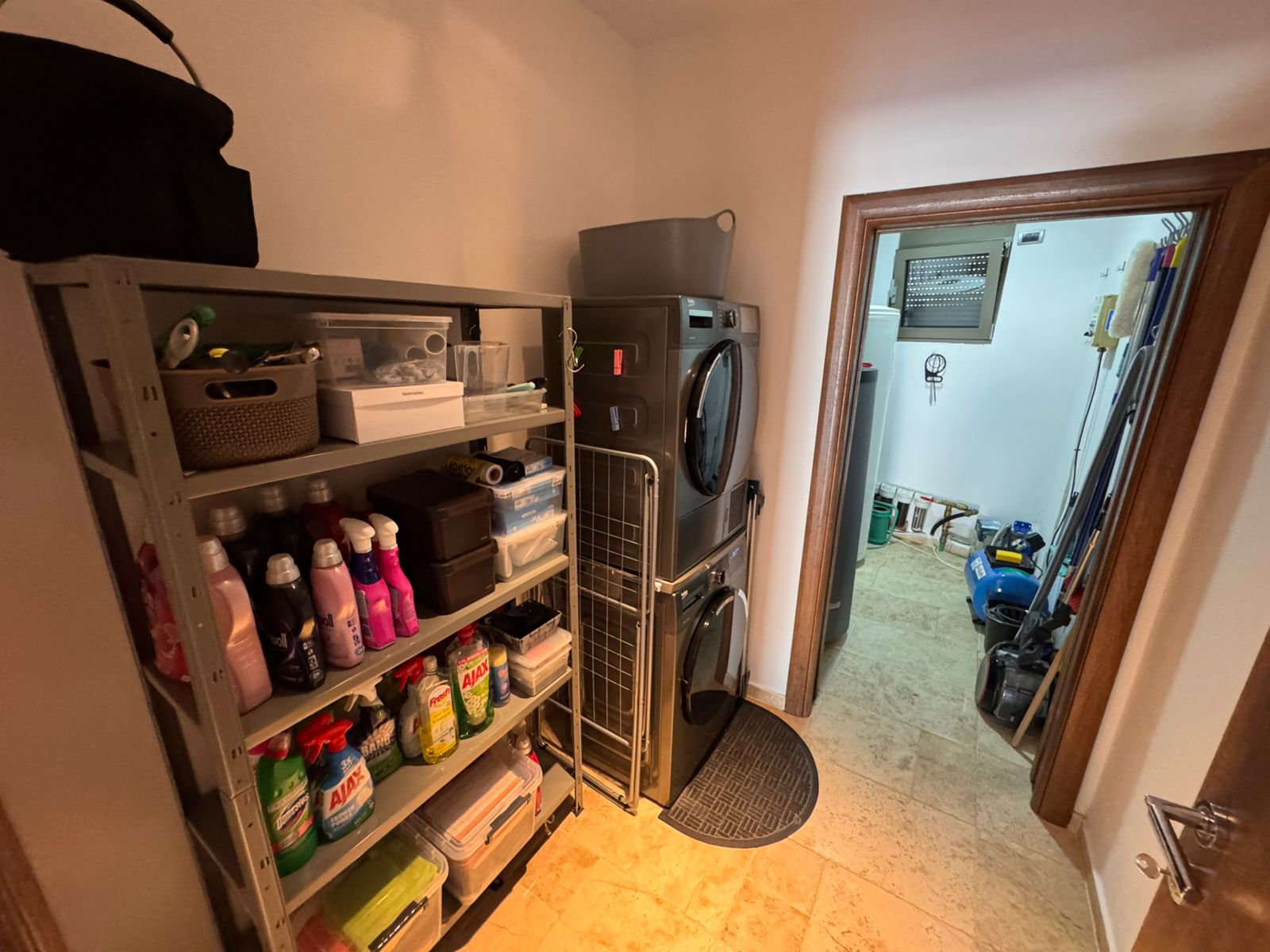 Modern laundry room with stacked washer-dryer, organized shelves, and utility area&mdash;ideal Ulcinj investment via immobilien.ekosphere.me by Ekosphere.