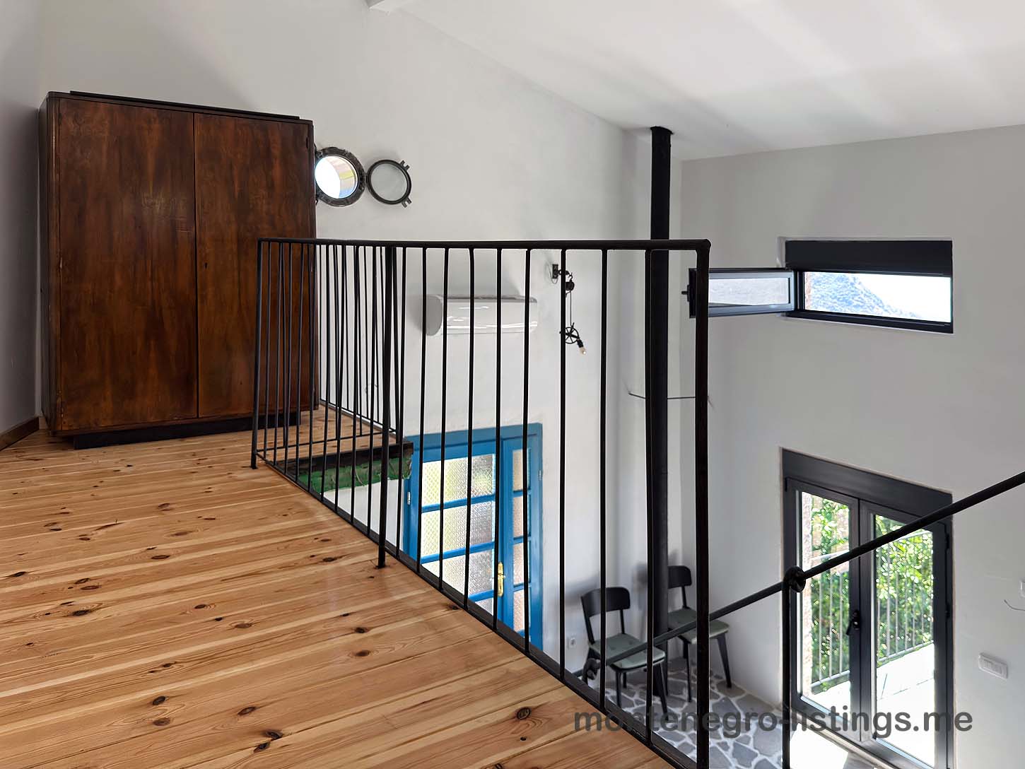 Elegant loft with wood floors, black metal railing, and large windows. Premier Ulcinj property listed by immobilien.ekosphere.me (ekosphere doo).
