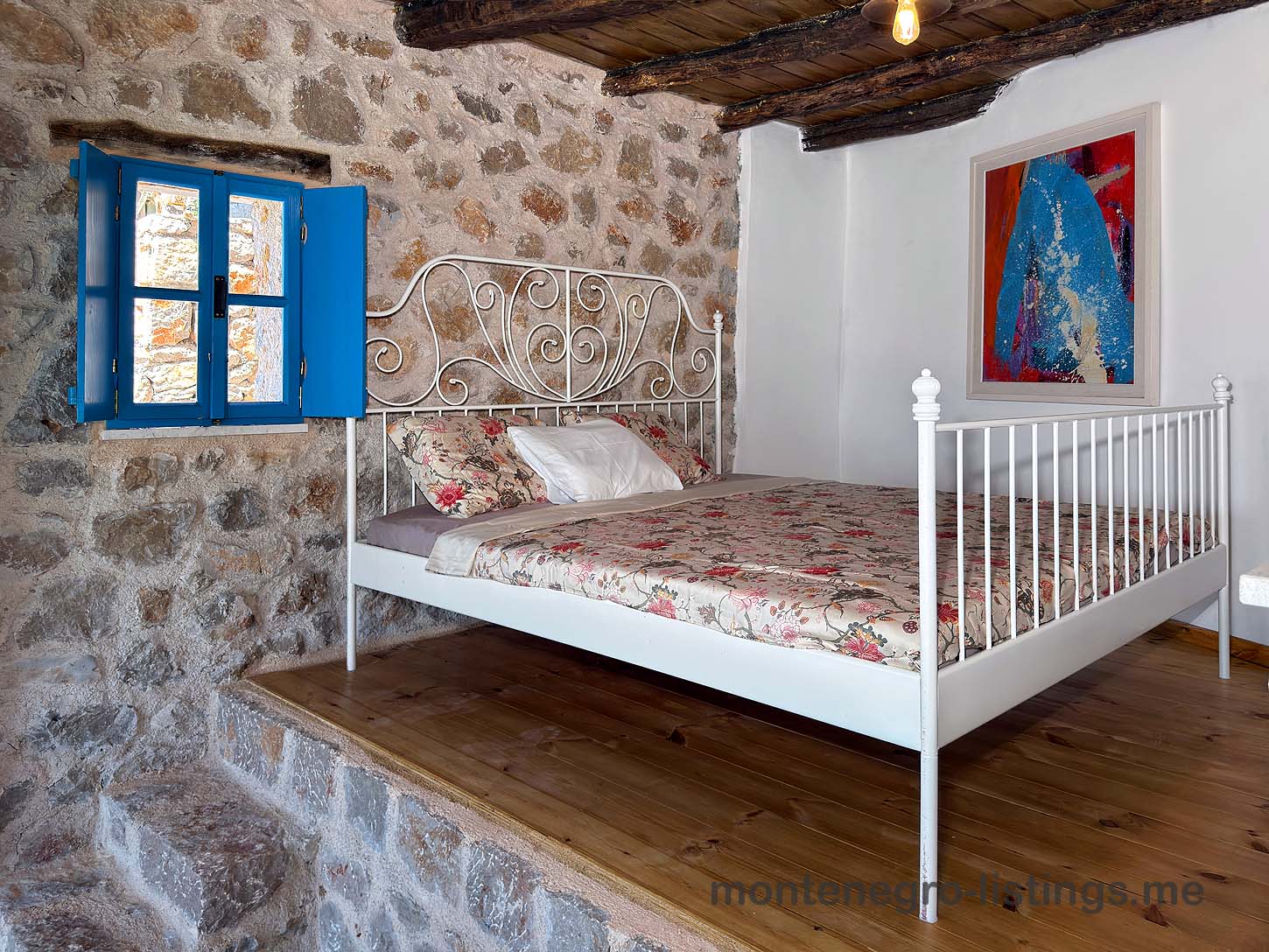 Charming Ulcinj property: stone-walled room, stylish white bed, wood platform&mdash;invest in Montenegro with immobilien.ekosphere.me by ekosphere doo.