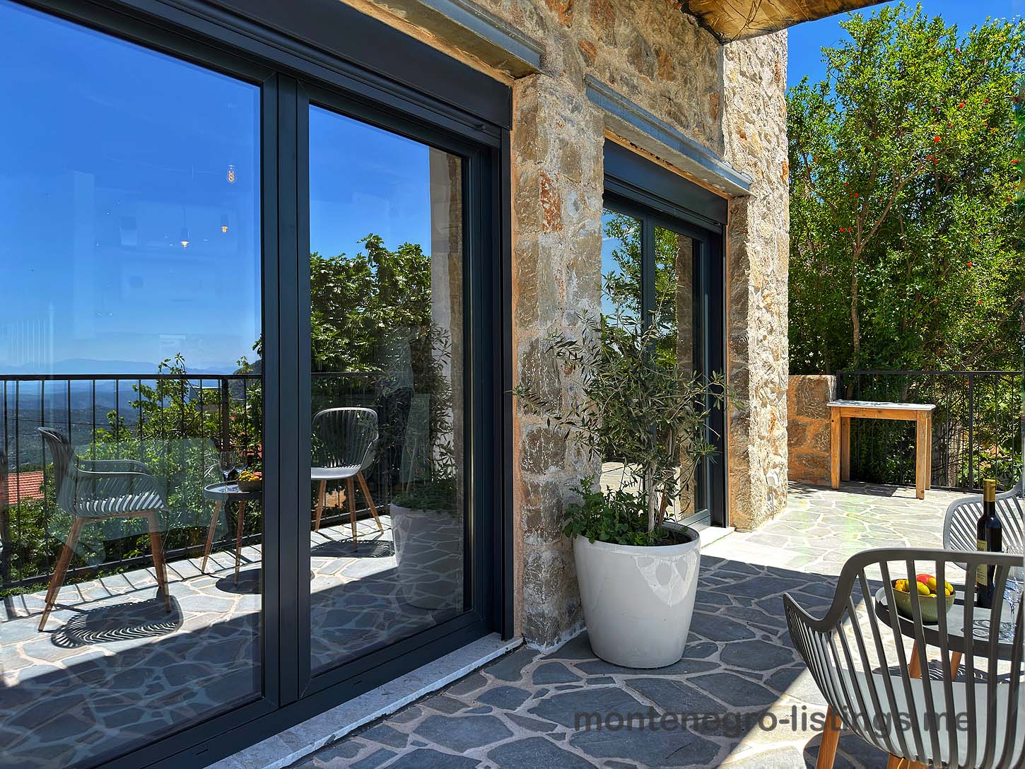 Elegant stone patio with sliding doors, stylish seating, and scenic views&mdash;prime Ulcinj Montenegro real estate by Ekosphere on immobilien.ekosphere.me.