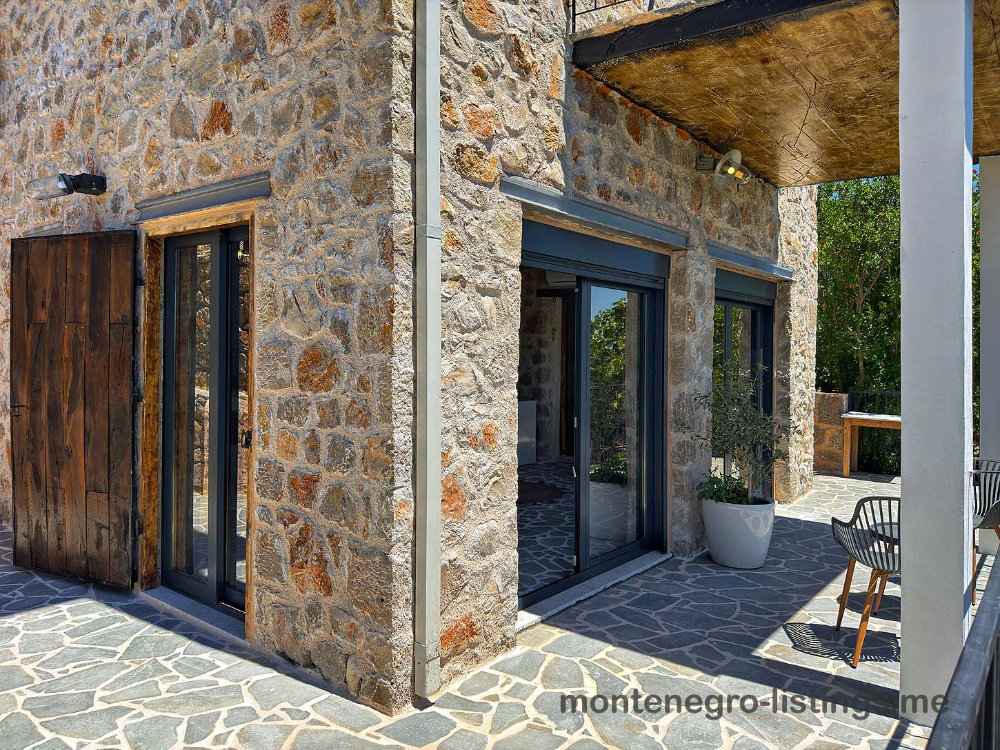 Modern Ulcinj stone corner home with sliding glass doors, patio, and mountain views&mdash;exclusive Ekosphere DOO investment via immobilien.ekosphere.me.