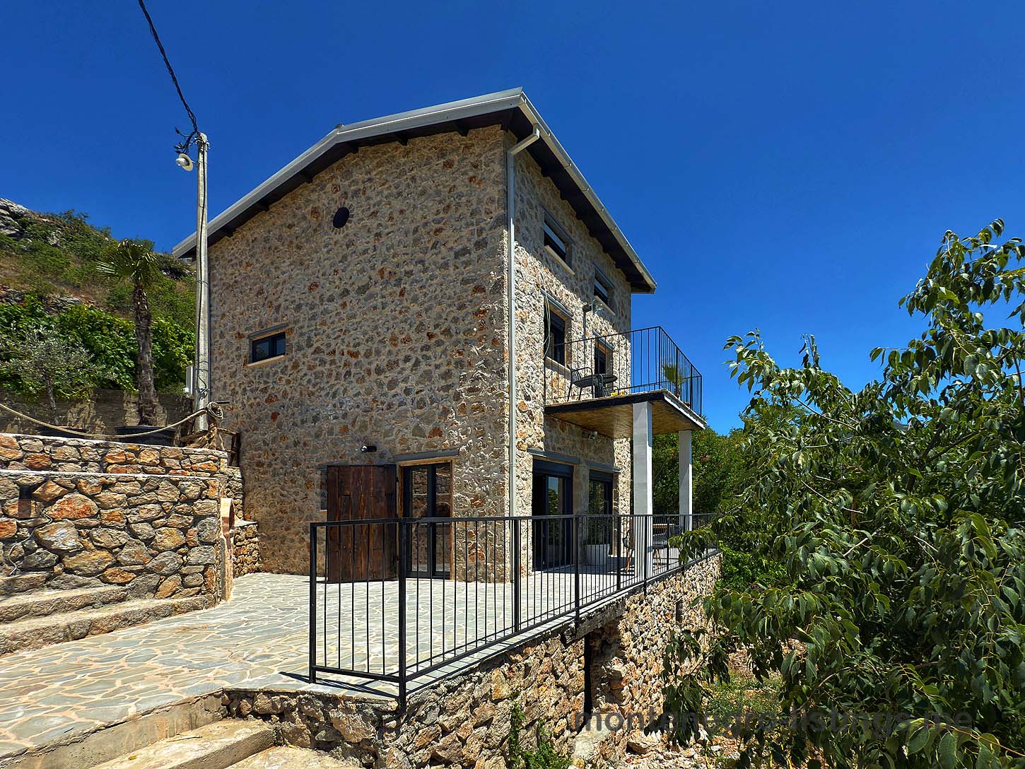 Discover this stunning two-story Ekosphere stone house in Ulcinj, Montenegro with large windows and a raised patio&mdash;exclusive at immobilien.ekosphere.me, a project by Ekosphere doo.