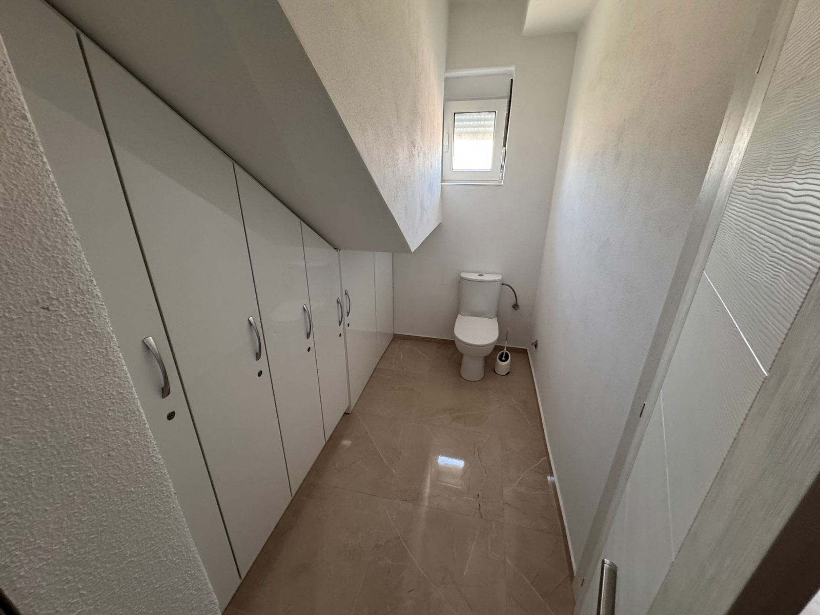 Modern narrow bathroom with slanted ceiling, elegant built-ins, and sleek tiling&mdash;exclusive Ulcinj property via immobilien.ekosphere.me by Ekosphere.